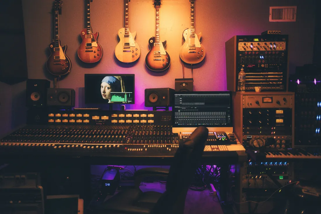 Zvukové studio s mixážním pultem, monitory a analogovým vybavením v tlumeném světle